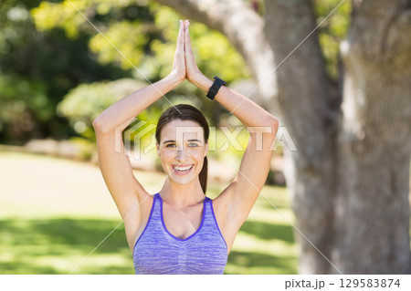 Woman raising arms above head in sunny park wearing purple tank top and fitness watch Woman raising arms above head in sunny park wearing purple tank top and fitness watch 129583874