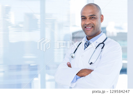 African American male doctor standing in clinic by blinds in lab coat, tie, stethoscope, copy space African American male doctor standing in clinic by blinds in lab coat, tie, stethoscope, copy space 129584247