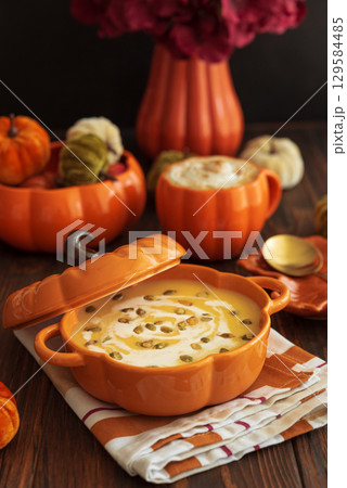 Autumnal lunch with pumpkin soup in a pumpkin-shaped bowl, pumpkin latte, croutons and festive decor on dark wooden table Autumnal lunch with pumpkin soup in a pumpkin-shaped bowl, pumpkin latte, croutons and festive decor on dark wooden table 129584485