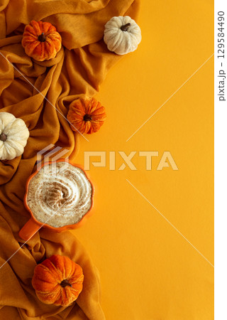 Pumpkin latte with whipped cream and spices, surrounded by autumn decor. Top view. Copy space 129584490