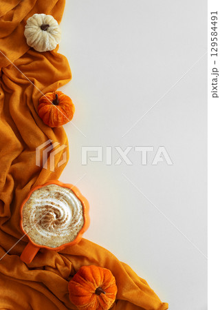 Pumpkin latte with whipped cream and spices, surrounded by autumn decor on white background. Copy space Pumpkin latte with whipped cream and spices, surrounded by autumn decor on white background. Copy space 129584491