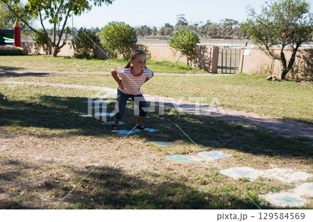 Female child playing on painted stepping stones in sunny backyard near inflatable bounce house Female child playing on painted stepping stones in sunny backyard near inflatable bounce house 129584569