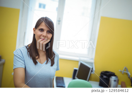 Woman standing in compact office, holding stainless steel flask near monitor, copy space Woman standing in compact office, holding stainless steel flask near monitor, copy space 129584612