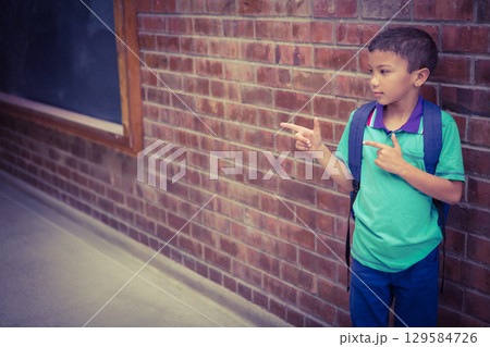 Asian boy leaning against wall beside chalkboard in school corridor carrying backpack, copy space Asian boy leaning against wall beside chalkboard in school corridor carrying backpack, copy space 129584726