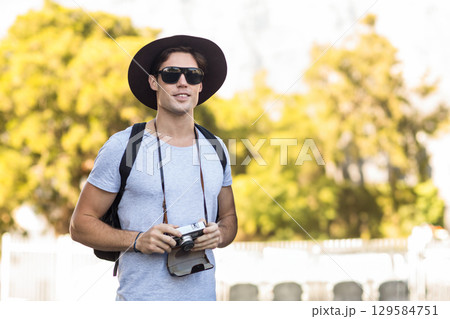 Male photographer holding rangefinder camera wearing wide-brim hat in sunny garden, copy space Male photographer holding rangefinder camera wearing wide-brim hat in sunny garden, copy space 129584751
