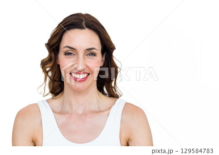 Woman in mid-thirties smiling wearing white tank top facing camera in studio with white backdrop Woman in mid-thirties smiling wearing white tank top facing camera in studio with white backdrop 129584783