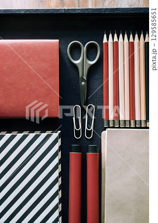 Organized workspace with stationery items on a black background ready for creative tasks 129585651