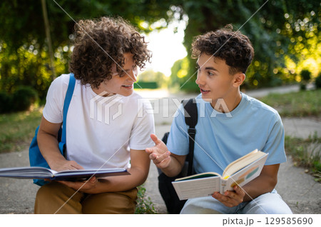 Two teens sitting in the park and studying together 129585690