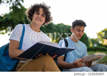 Two teens sitting in the park and studying together 129585697
