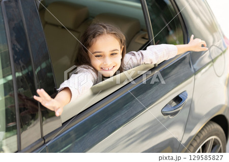 Pretty little girl looking out of the car window and feeling excited 129585827