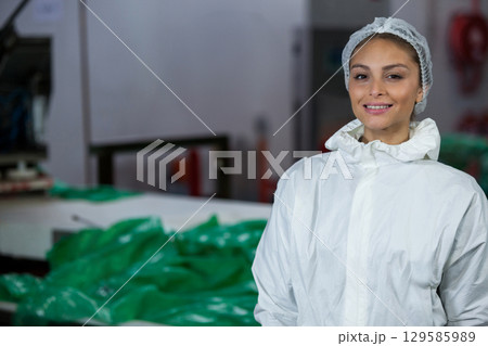 Woman wearing coverall sorting plastic sheets by control panel at factory metal table, copy space 129585989