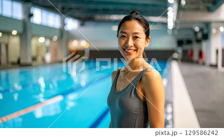 水泳後に水着姿でプールサイドで笑顔の女性 129586242