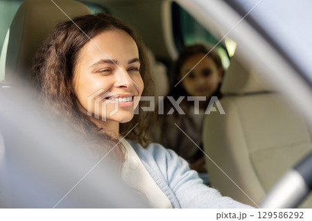 Young woman and her daughter sitting in the car and looking joyful Young woman and her daughter sitting in the car and looking joyful 129586292