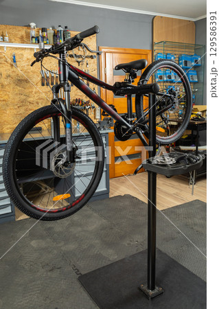 Bicycle in home garage workshop on stand surrounded by tools and equipment Bicycle in home garage workshop on stand surrounded by tools and equipment 129586391