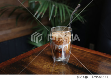 Traditional Vietnamese egg coffee with condensed milk and creamy foam on wooden table in a glass, copy space. Concept of enjoying unique Asian beverage and cultural coffee experience. 129586544