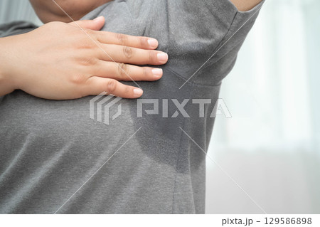 Sweaty underarms, Asian woman with sweat on clothes under armpit. Sweaty underarms, Asian woman with sweat on clothes under armpit. 129586898