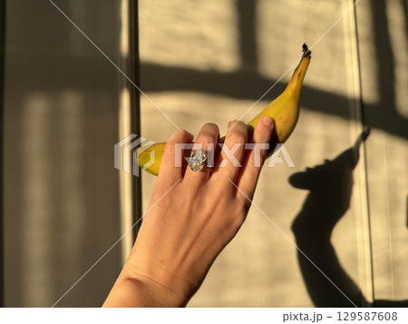 Oval diamond engagement ring with banana against shadowed wall 129587608