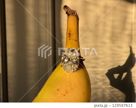 Diamond engagement ring beside banana in warm sunlight Diamond engagement ring beside banana in warm sunlight 129587613