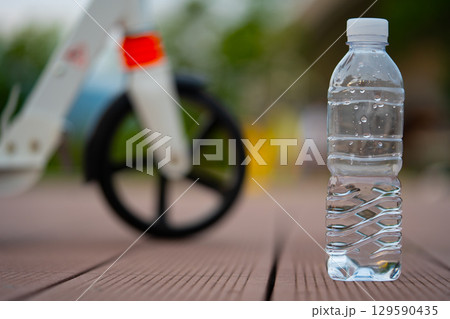 A bottle of clean water and a scooter wheel. After exercise on a summer evening. A bottle of clean water and a scooter wheel. After exercise on a summer evening. 129590435
