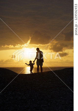 Father and Son Silhouettes at Sunset. Family Bonding Moment 129592453