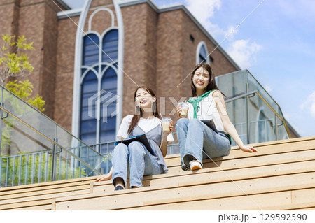 友達とキャンパスの階段ベンチに座る大学生 129592590