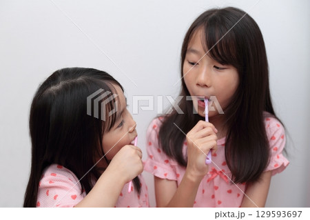 パジャマで歯磨きをする4歳と10歳の姉妹の女の子 パジャマで歯磨きをする4歳と10歳の姉妹の女の子 129593697