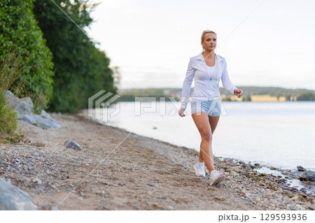 Woman walking on a scenic lakeside trail in a sporty fitness outfit 129593936