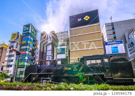 日本の東京都市景観8月8日。夏空が広がる新橋・新橋SL広場前のSLや飲み屋街などを望む 129594179