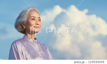 女性が優雅な装いでそっと空を見つめる静かな瞬間 女性が優雅な装いでそっと空を見つめる静かな瞬間 129595049