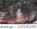 Weathered ancient natural rock wall with black stains 129595268
