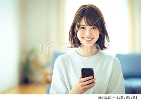 スマホを手に持っている笑顔の女性 129595291