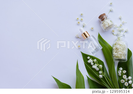 Glass bottle of lily of the valley essential oil with fresh flowers. Copy space. 129595314
