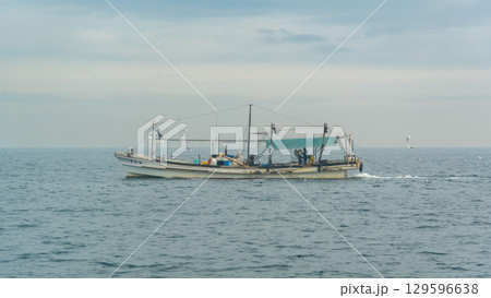 A lone fishing boat on a calm sea under a cloudy sky in Osaka bay in Japan A lone fishing boat on a calm sea under a cloudy sky in Osaka bay in Japan 129596638