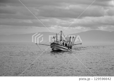A lone fishing boat on a calm sea under a cloudy sky in Osaka bay in Japan 129596642