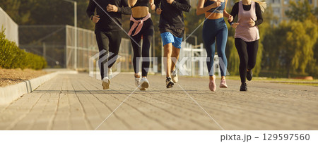 Cropped photo of a people jogging along a path in the park having sport workout in nature. Cropped photo of a people jogging along a path in the park having sport workout in nature. 129597560
