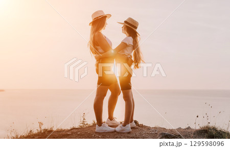 Two Women Embracing at Sunset Overlooking the Ocean Two Women Embracing at Sunset Overlooking the Ocean 129598096