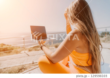 Woman in Yellow Outfit Using Laptop on a Sunny Day 129598103