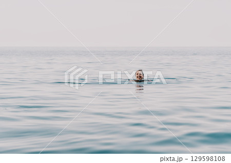Ocean Swimmer Silhouette Water A lone swimmer is seen in the distance, a dark silhouette against the vast expanse of the ocean, as the sun dips below the horizon and the sky turns a soft orange. Ocean Swimmer Silhouette Water A lone swimmer is seen in the distance, a dark silhouette against the vast expanse of the ocean, as the sun dips below the horizon and the sky turns a soft orange. 129598108