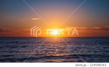 glowing sun setting over calm ocean radiating warmth and positive vibes glowing sun setting over calm ocean radiating warmth and positive vibes 129598163