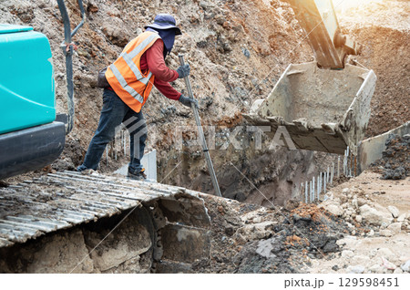 Workers are working on the construction of a drainage pipe within the construction area. 129598451