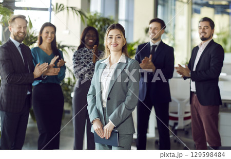 Smiling beautiful female professional leader manager standing looking at camera in office Smiling beautiful female professional leader manager standing looking at camera in office 129598484