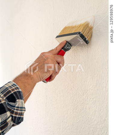 House painter worker painting a wall white. Building. 129598976