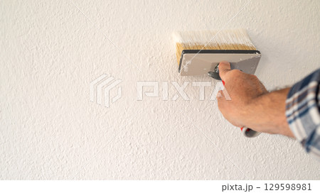 House painter worker painting a wall white. Building. 129598981
