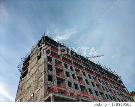 View from below of construction of a multi-story building with a monolithic reinforced concrete frame and walls made of gas blocks. Special safety nets are stretched to prevent workers from falling View from below of construction of a multi-story building with a monolithic reinforced concrete frame and walls made of gas blocks. Special safety nets are stretched to prevent workers from falling 129599563