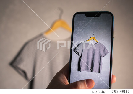 Woman taking photo of her old clothes for resale. Second hand concept. Closet organization. Woman taking photo of her old clothes for resale. Second hand concept. Closet organization. 129599937