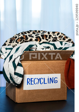 Box of used clothing marked for recycling. Eco friendly lifestyle. Closet management. 129599940