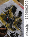 Skilled individual meticulously paints sheet of paper using brush 129600209