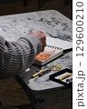Specialist in grey sweater sketches in open notebook 129600210
