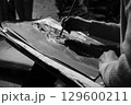 Artist paints monochrome picture on sheet of paper with brush 129600211