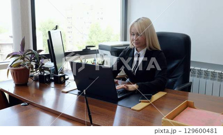 Focused businesswoman working on laptop at her organized desk in a modern office, showcasing professionalism and productivity Focused businesswoman working on laptop at her organized desk in a modern office, showcasing professionalism and productivity 129600481